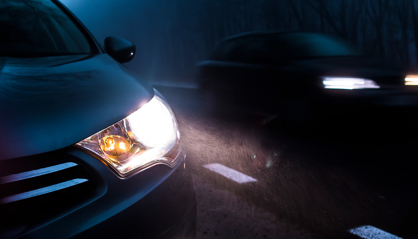 Closeup of car headlights on, driving at night